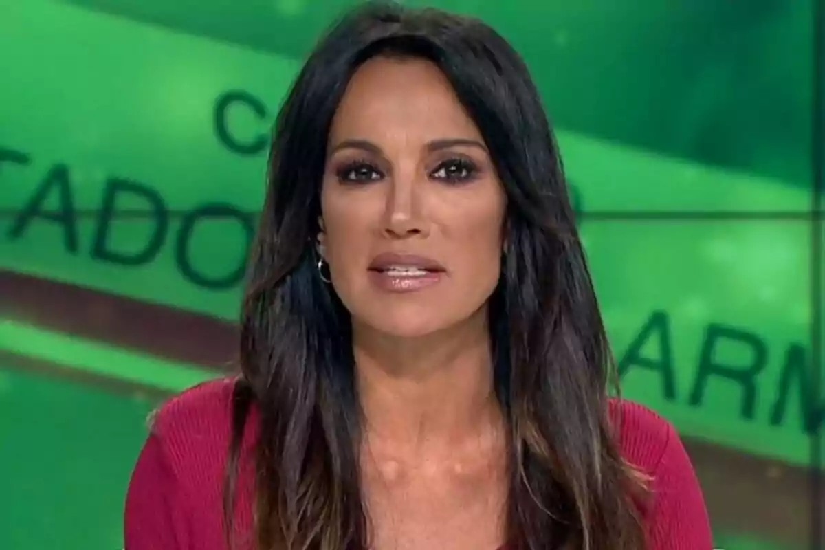 Cristina Saavedra de cabell llarg i fosc amb jersei vermell parlant davant d’una pantalla verda amb lletres desenfocades a laSexta Notícies