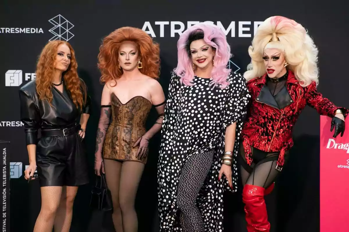 Ana Locking, Le Cocó, Supremme de Luxe y Samantha Ballentines posan en una alfombra roja con atuendos llamativos y maquillaje elaborado frente a un fondo con logotipos de Atresmedia y Drag Race Ana Locking, Le Cocó, Supremme de Luxe y Samantha Ballentines posan en una alfombra roja con atuendos llamativos y maquillaje elaborado frente a un fondo con logotipos de Atresmedia y Drag Race