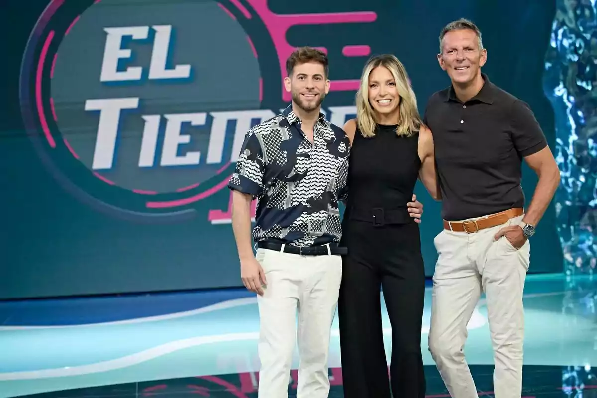 César Muñoz, María Ruiz y Joaquín Prat sonríen y posan juntas en un set de televisión con un fondo que muestra el texto El Tiempo Justo César Muñoz, María Ruiz y Joaquín Prat sonríen y posan juntas en un set de televisión con un fondo que muestra el texto El Tiempo Justo