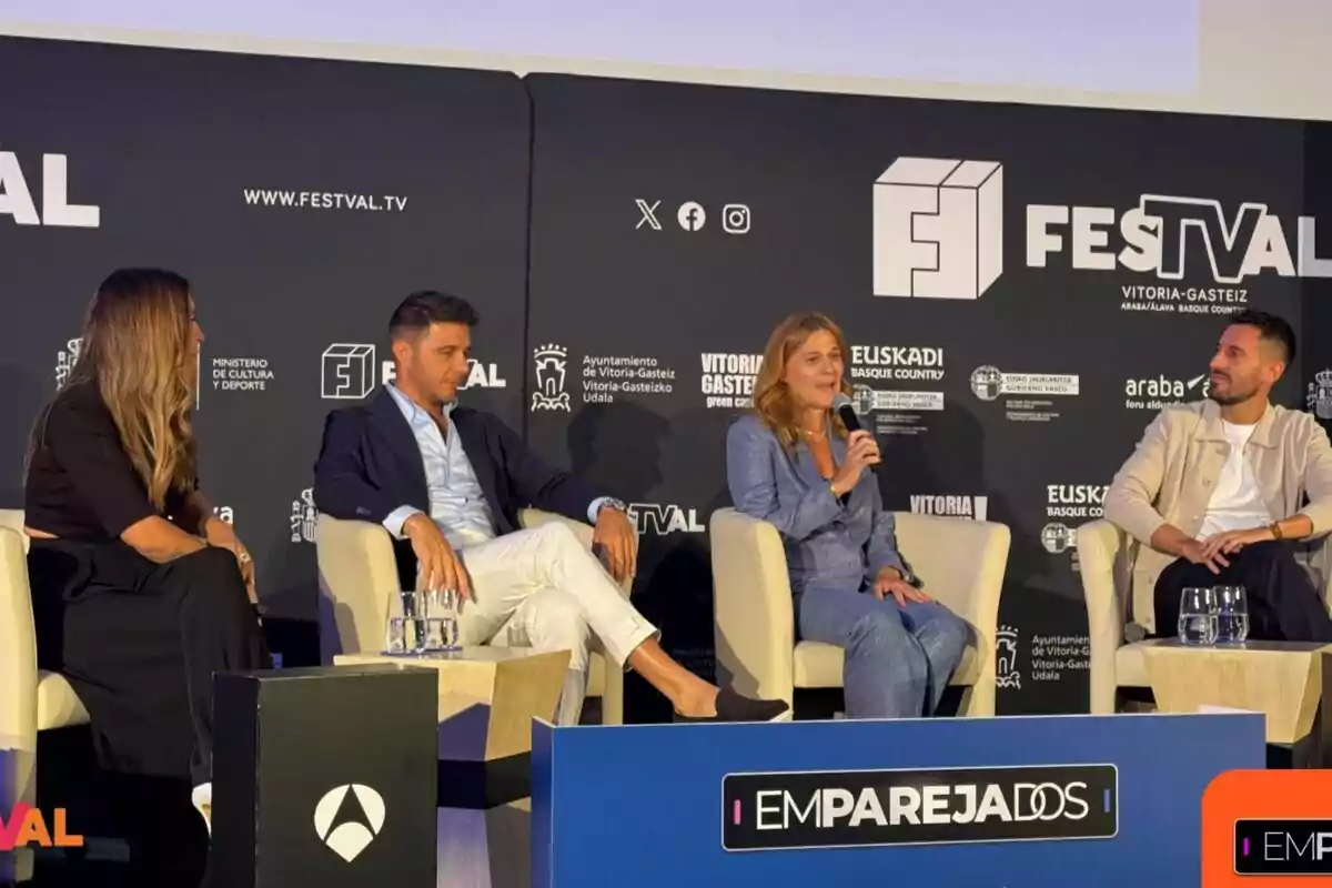 Susana Saborido, Joaquín Sánchez, Carmen Ferreiro y Javier Ruiz sentadps en sillones blancos participan en una charla sobre Emparejados en un escenario con fondo negro decorado con logotipos de FESTVAL y otras instituciones, una de ellas sostiene un micrófono mientras las demás escuchan atentamente.