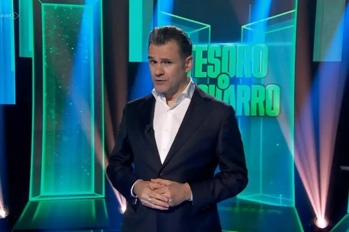 Ikaki López amb vestit fosc i camisa blanca està dret en un plató de televisió amb llums blaves i verdes i un rètol de fons que diu TRESOR O FERRALLA Ikaki López amb vestit fosc i camisa blanca està dret en un plató de televisió amb llums blaves i verdes i un rètol de fons que diu TRESOR O FERRALLA