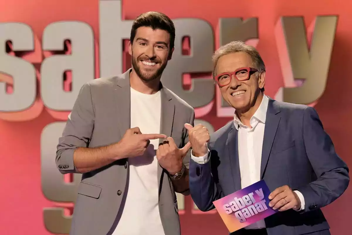 Rodrigo Vázquez i Jordi Hurtado somrients posen al plató de Saber i guanyar amb un fons acolorit i una targeta que diu saber i guanyar Rodrigo Vázquez i Jordi Hurtado somrients posen al plató de Saber i guanyar amb un fons acolorit i una targeta que diu saber i guanyar