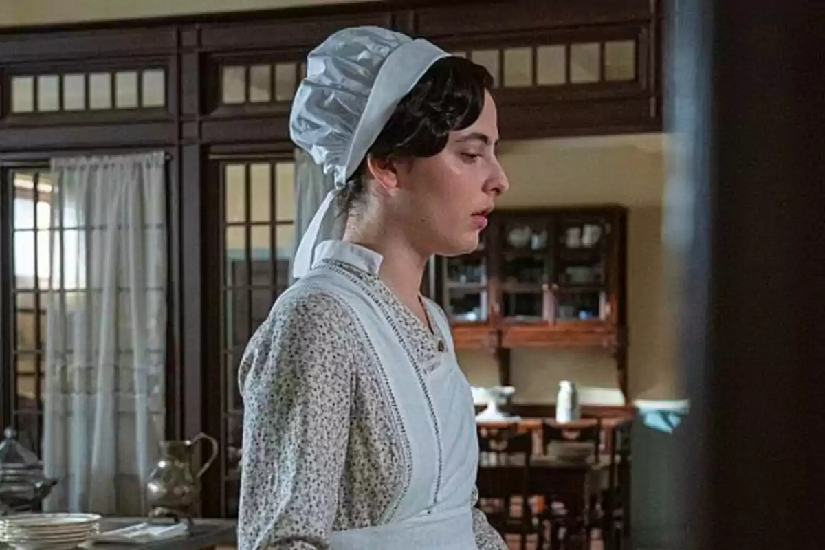 Vera vestida con uniforme de sirvienta antiguo y cofia blanca en una cocina antigua. Captura de 'La Promesa' Vera vestida con uniforme de sirvienta antiguo y cofia blanca en una cocina antigua. Captura de 'La Promesa'