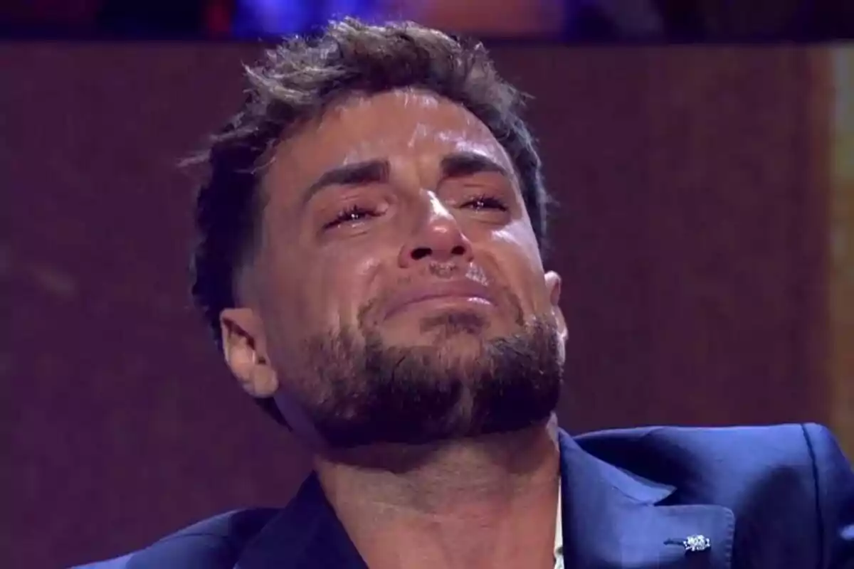 Montoya con barba y cabello corto llorando con expresión de tristeza en un entorno iluminado de De Viernes