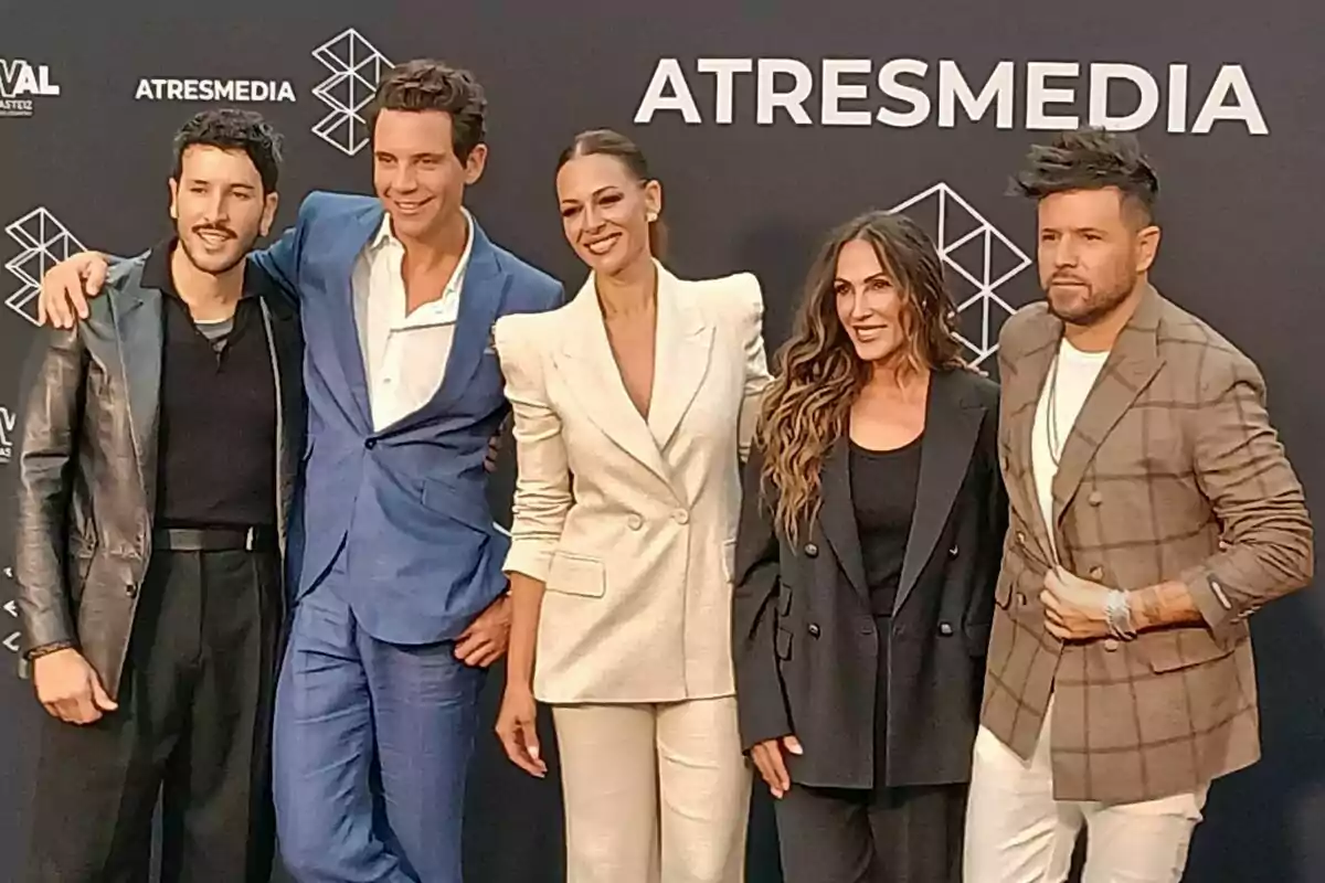 Sebastian Yatra, Mika, Eva González, Malú i Pablo López posen somrients davant d’un fons amb el logotip d’Atresmedia i La Voz, tots vestits de manera elegant i formal.