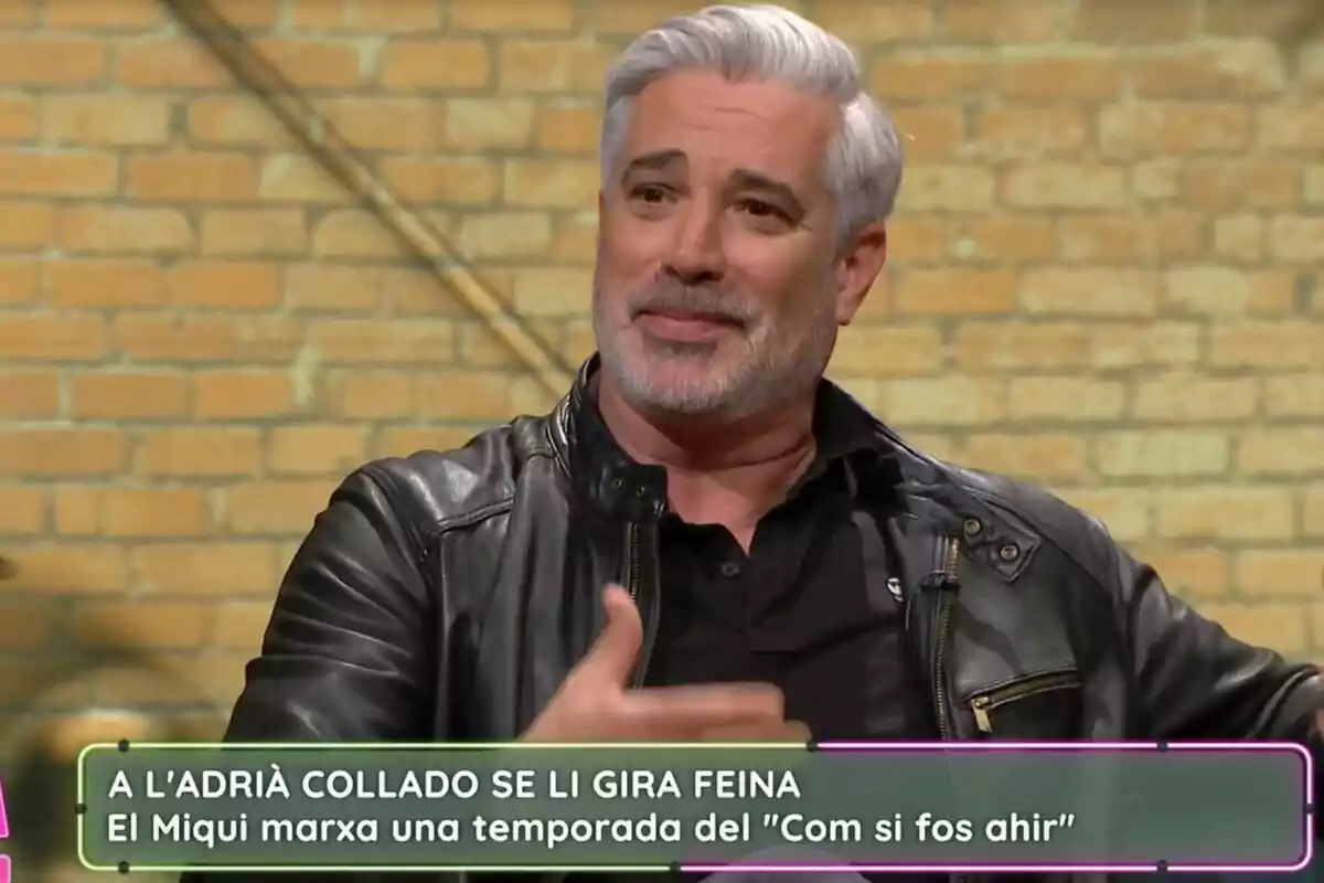 Adrià Collado de cabell canós i barba està assegut a La Selva, vestint una jaqueta de cuir negra, amb un fons de maons i un text a la part inferior de la imatge.