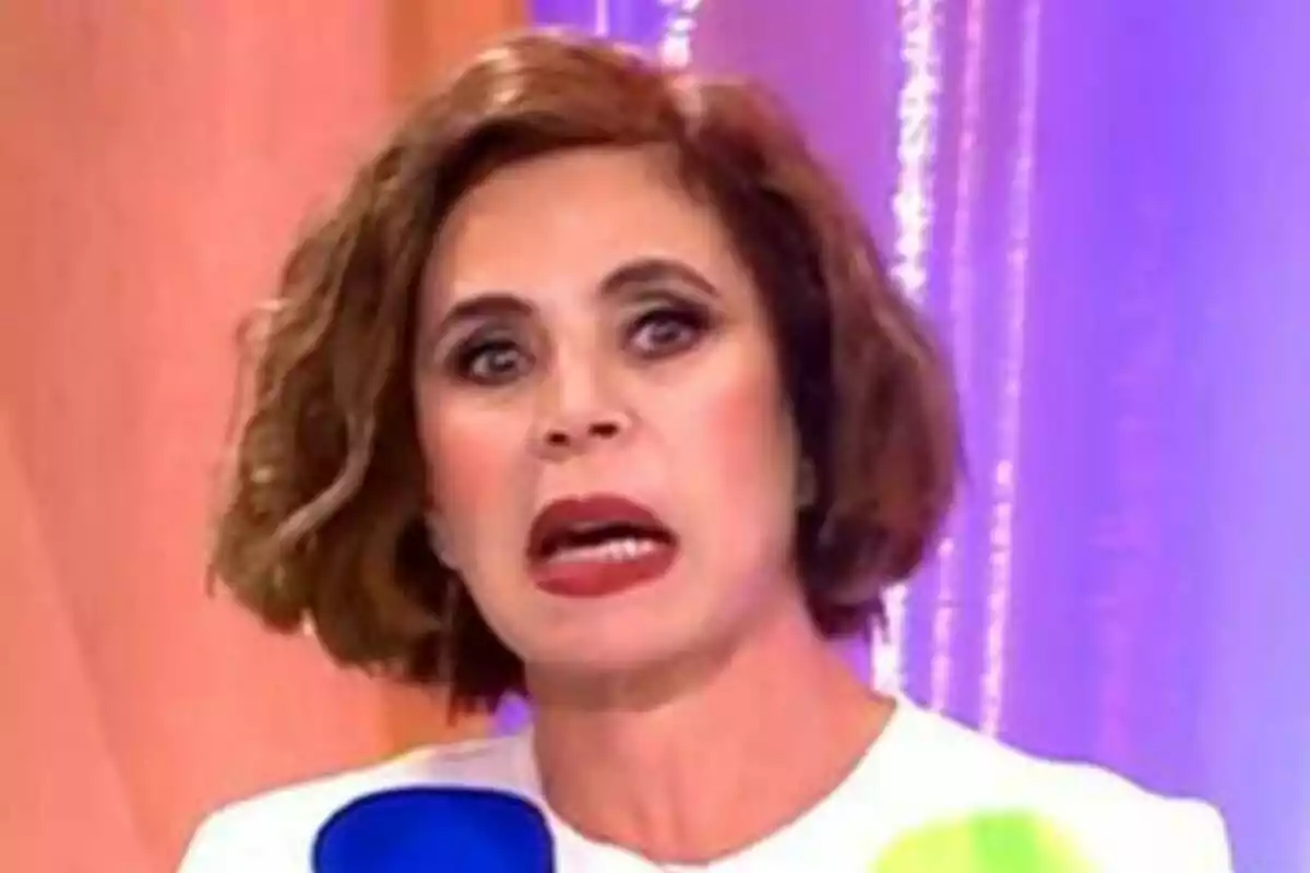 Ágatha Ruiz de la Prada con expresión facial sorprendente en un fondo colorido en Fiesta. Ágatha Ruiz de la Prada con expresión facial sorprendente en un fondo colorido en Fiesta.