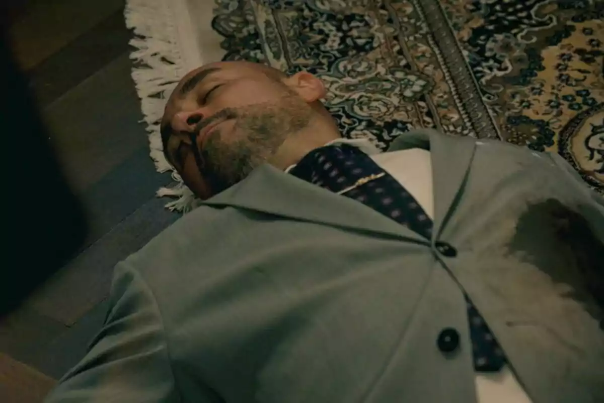 Alain Hernández con traje gris está acostado en el suelo sobre una alfombra decorativa en Sueños de Libertad. Alain Hernández con traje gris está acostado en el suelo sobre una alfombra decorativa en Sueños de Libertad.