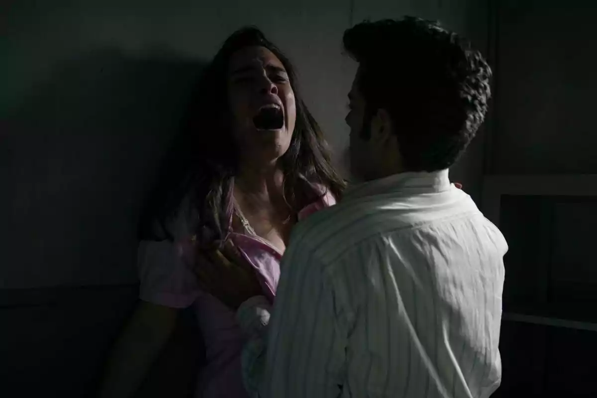 Alba Brunet con expresión de angustia es sujetada por un hombre en una habitación oscura en Sueños de Libertad. Alba Brunet con expresión de angustia es sujetada por un hombre en una habitación oscura en Sueños de Libertad.