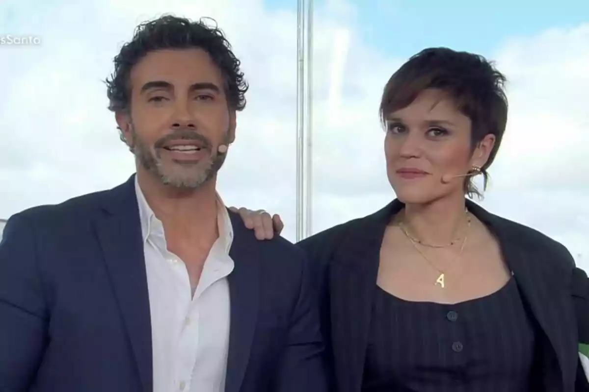 Alberto Herrera i Miriam Moreno amb micròfons a l'orella, una dona i un home, posen junts davant d'una finestra amb cel blau de fons a Mañaneros. Alberto Herrera i Miriam Moreno amb micròfons a l'orella, una dona i un home, posen junts davant d'una finestra amb cel blau de fons a Mañaneros.