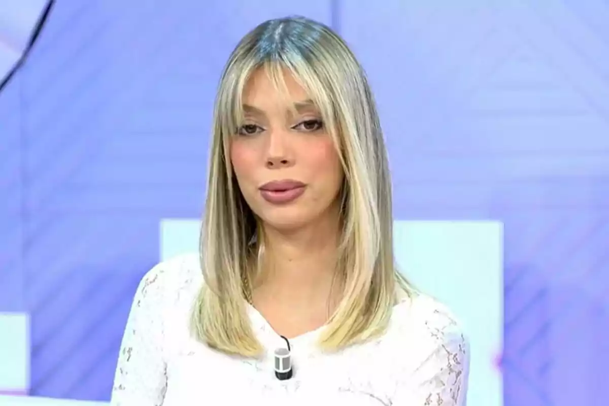 Plano corto de Alejandra Rubio con cabello rubio lacio y flequillo usando una blusa blanca en un entorno de estudio de televisión.