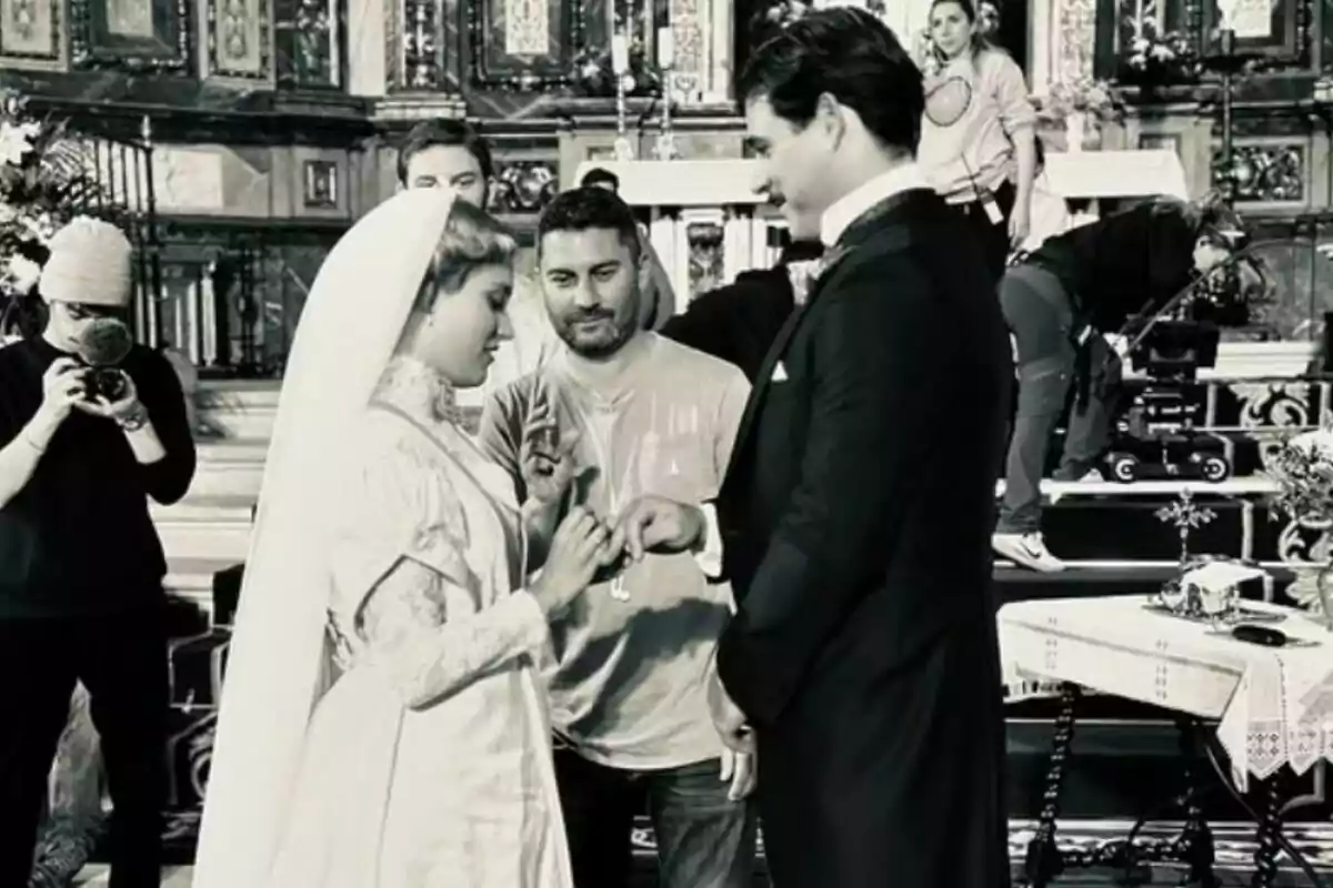 Una escena de rodatge mostra Ana Garcés i Arturo Sancho vestits de nuvis en un set de filmació amb l'equip de producció treballant al voltant de La Promesa. Una escena de rodatge mostra Ana Garcés i Arturo Sancho vestits de nuvis en un set de filmació amb l'equip de producció treballant al voltant de La Promesa.