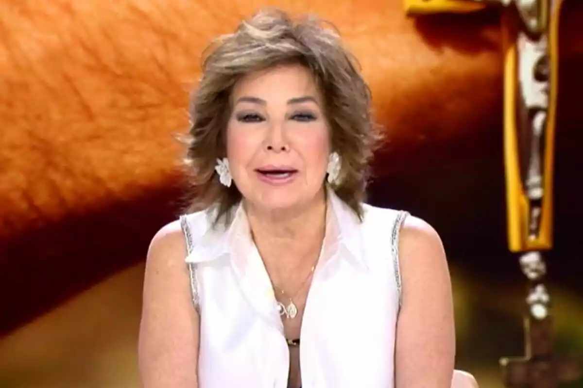 Captura de Ana Rosa Quintana en TardeAR vestida con una blusa blanca, hablando frente a un micrófono con un fondo borroso. Captura de Ana Rosa Quintana en TardeAR vestida con una blusa blanca, hablando frente a un micrófono con un fondo borroso.