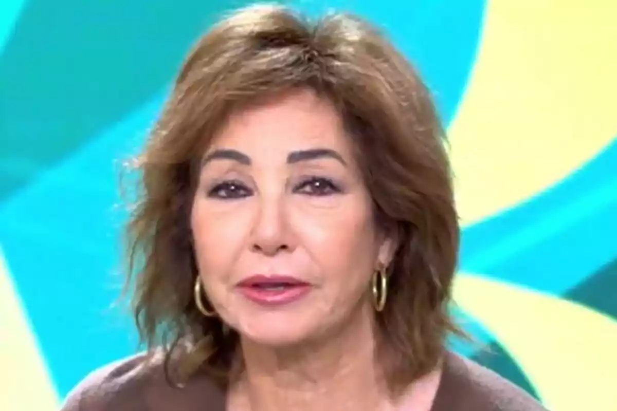 Ana Rosa Quintana amb cabell castany i arracades daurades davant d'un fons acolorit a El Programa de Ana Rosa. Ana Rosa Quintana amb cabell castany i arracades daurades davant d'un fons acolorit a El Programa de Ana Rosa.