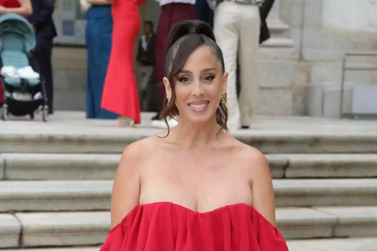 Anabel Pantoja con vestido rojo posando frente a unas escaleras con personas en el fondo. Anabel Pantoja con vestido rojo posando frente a unas escaleras con personas en el fondo.