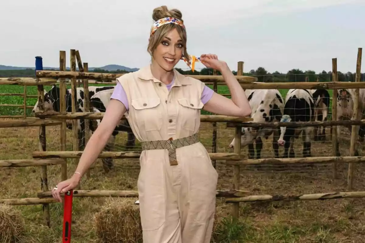 Anna Simón somrient en una granja amb vaques al fons, vestida amb un mico beix i una cinta als cabells presentant 'El Tros'