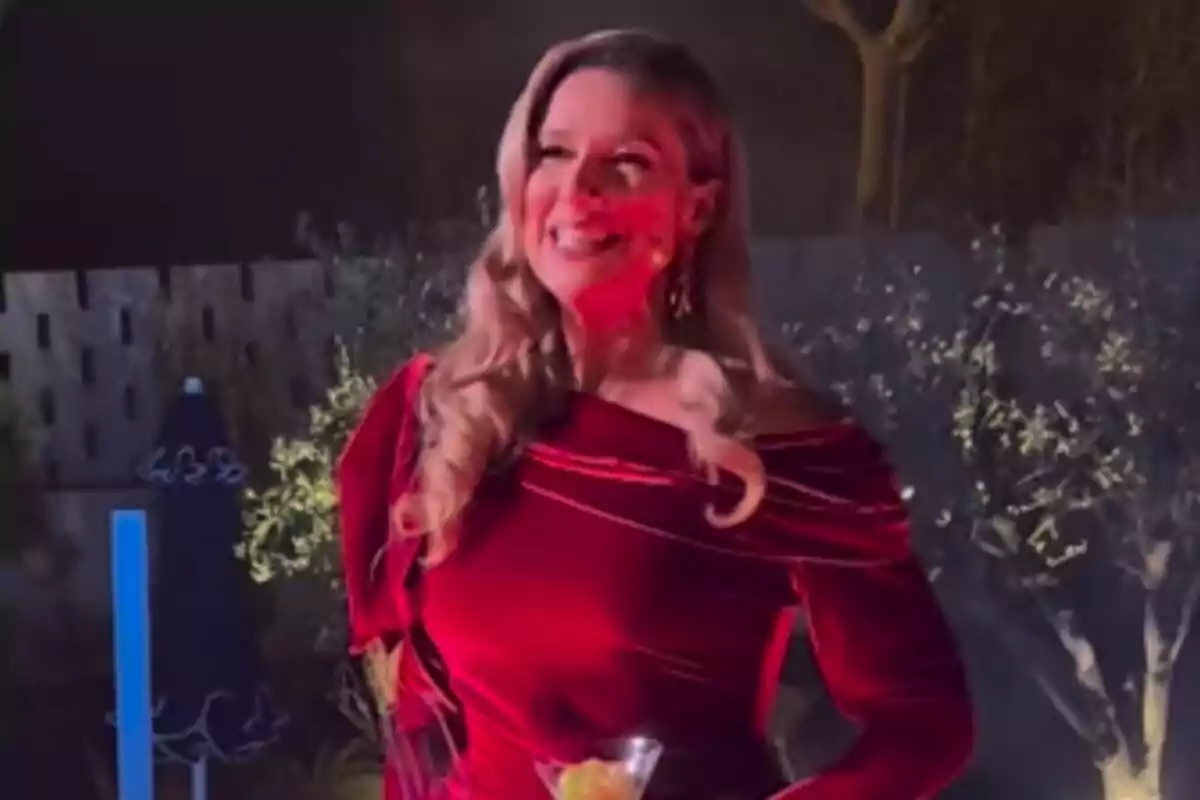 Anne Igartiburu sonriente con un vestido rojo en un entorno al aire libre iluminado.