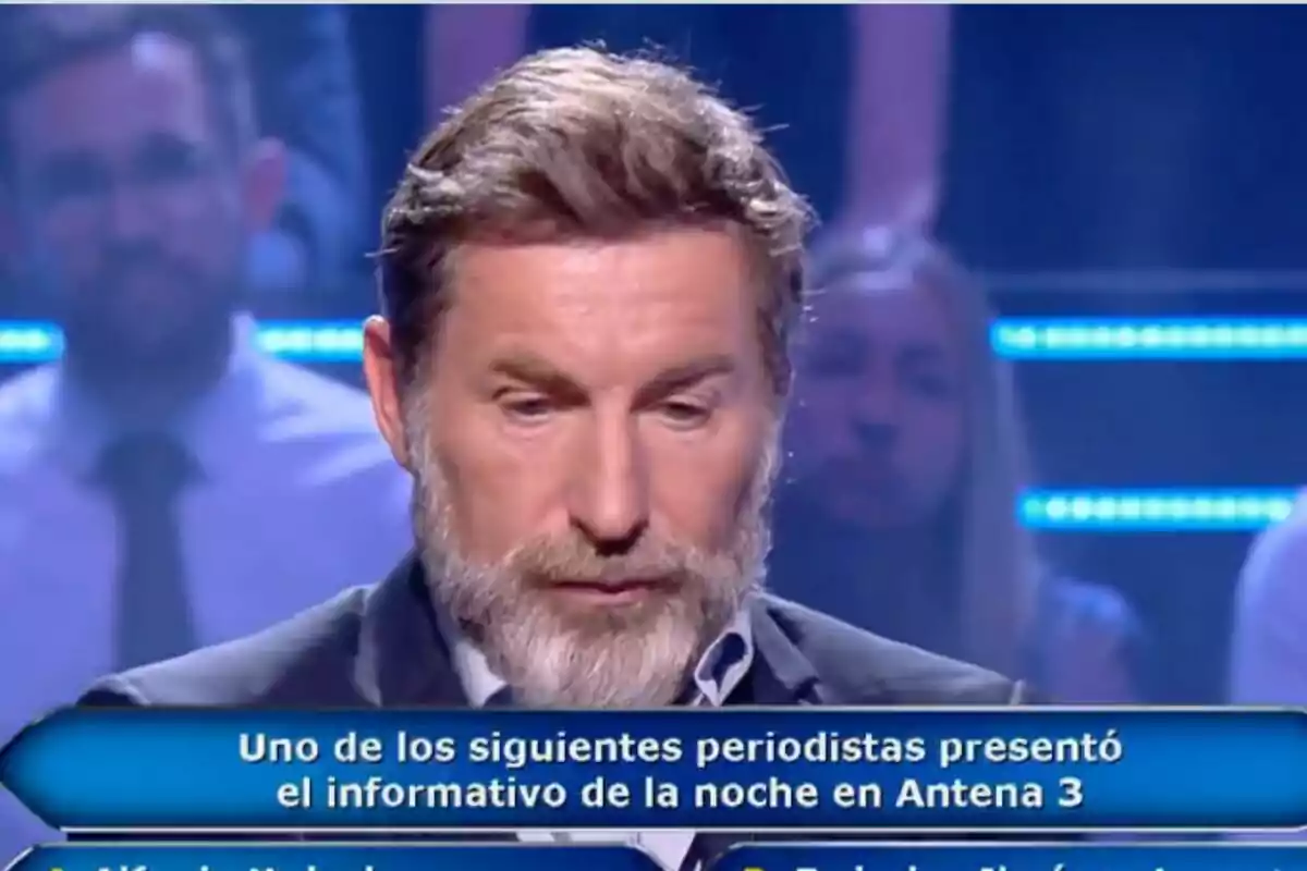 Antonio De la Torre con barba y cabello canoso aparece en un programa de televisión tipo concurso, 'Quien quiere ser millonario', mirando hacia abajo con expresión seria; en la parte inferior de la imagen hay una pregunta sobre periodistas que presentaron un informativo en Antena 3.