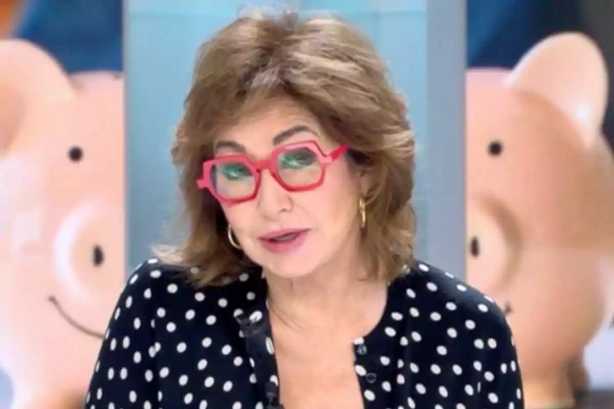 Ana Rosa Quintana amb ulleres vermelles i brusa de llunes en un estudi de televisió amb fons de porquets somrients a 'El programa de Ana Rosa'.