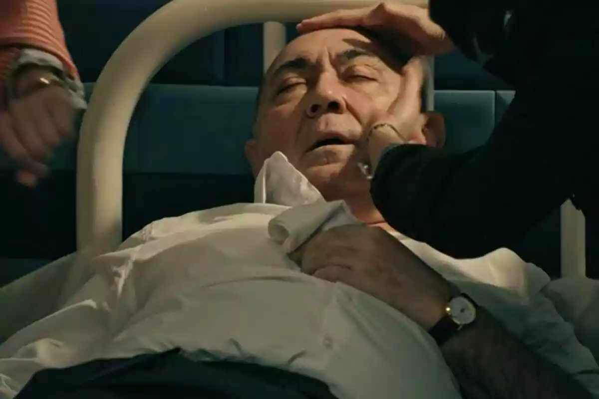 Arturo Querejeta mayor está acostado en una cama con los ojos cerrados mientras dos personas lo asisten tocándole la frente y el rostro en Sueños de Libertad. Arturo Querejeta mayor está acostado en una cama con los ojos cerrados mientras dos personas lo asisten tocándole la frente y el rostro en Sueños de Libertad.