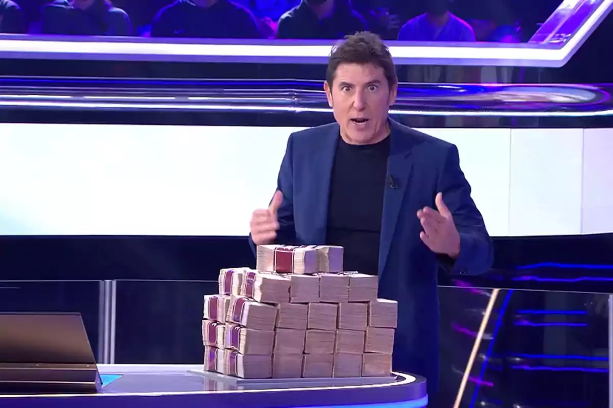 Manel Fuentes en un set de televisió amb una gran pila de bitllets. Captura d''Atrapa un millón' Manel Fuentes en un set de televisió amb una gran pila de bitllets. Captura d''Atrapa un millón'