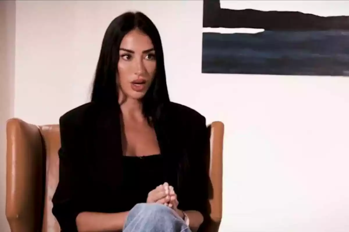 Aurah Ruiz de cabello oscuro sentada en un sillón con expresión seria y fondo de pared blanca con cuadro abstracto en De Viernes. Aurah Ruiz de cabello oscuro sentada en un sillón con expresión seria y fondo de pared blanca con cuadro abstracto en De Viernes.