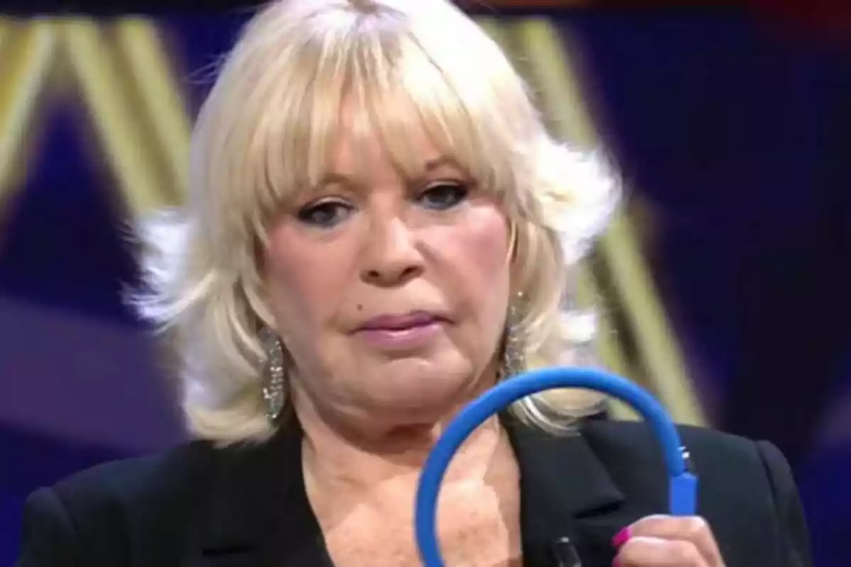 Bárbara Rey rubia de expresión seria sostiene un objeto azul circular en De Viernes