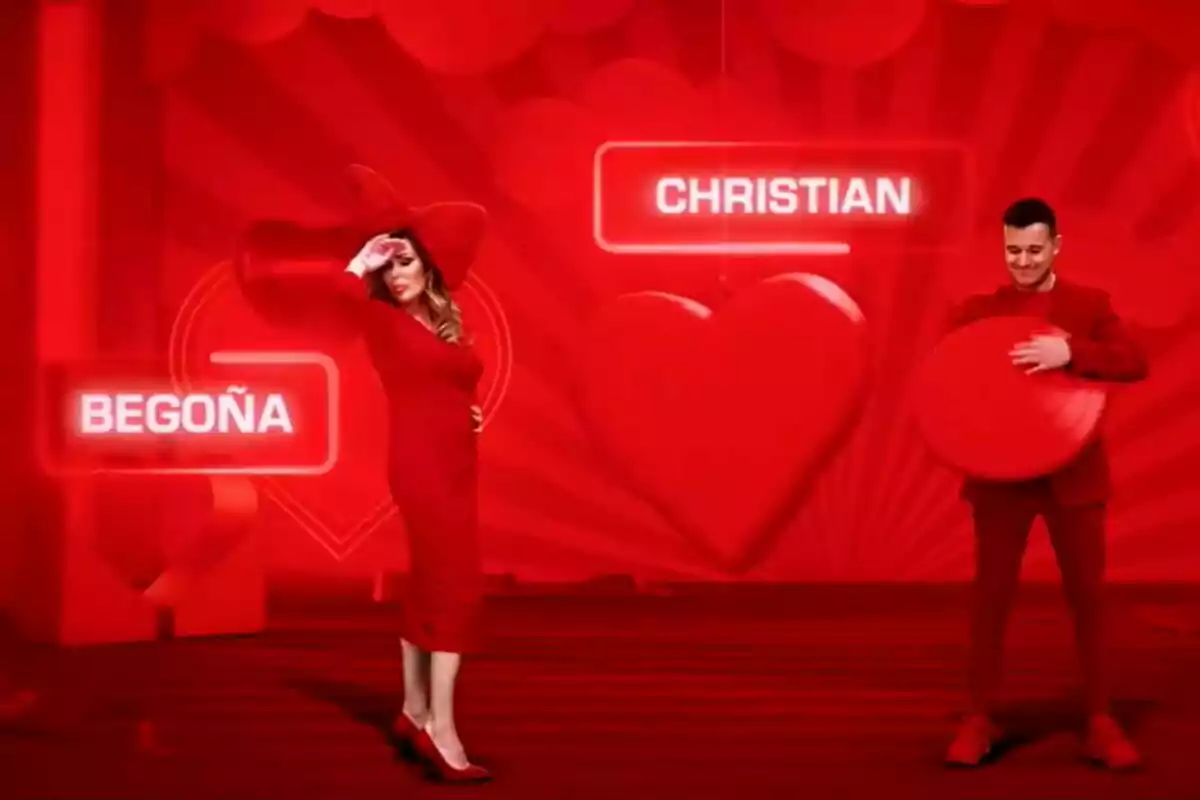 Captura de Begoña Gutiérrez con su hijo Christian vestidas de rojo posan en un escenario rojo con decoraciones de corazones y sus nombres, Begoña y Christian, iluminados en letreros en la promo de ¿Quién quiere casarse con mi hijo? Captura de Begoña Gutiérrez con su hijo Christian vestidas de rojo posan en un escenario rojo con decoraciones de corazones y sus nombres, Begoña y Christian, iluminados en letreros en la promo de ¿Quién quiere casarse con mi hijo?