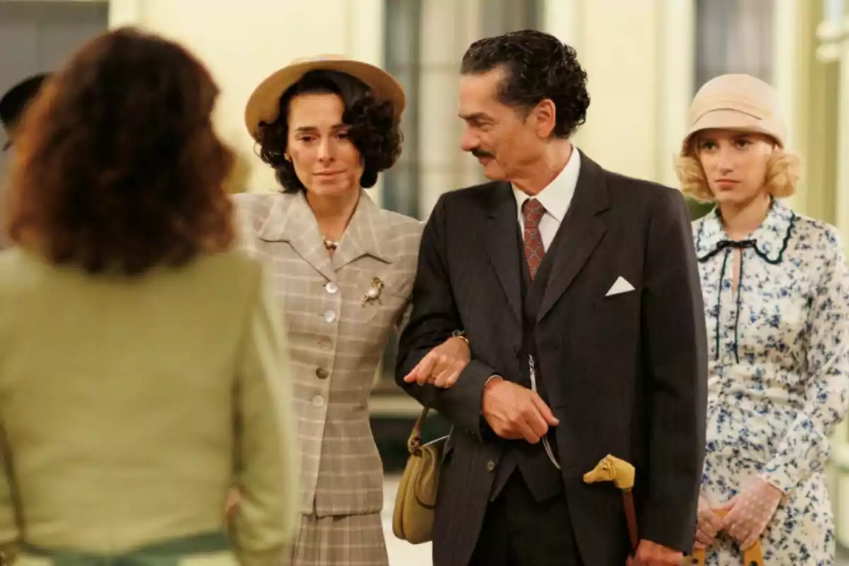 Carles Sanjaime y Begoña Maestre junto a otras personas vestidas con ropa de época en una escena interior en la serie La Moderna. Carles Sanjaime y Begoña Maestre junto a otras personas vestidas con ropa de época en una escena interior en la serie La Moderna.