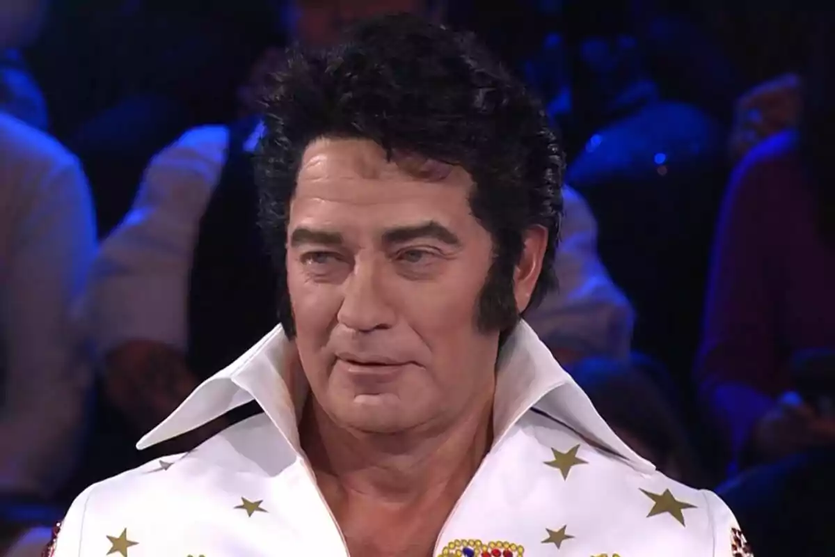 Bertín Osborne con un peinado voluminoso y patillas, vestido con un traje blanco adornado con estrellas doradas, en un ambiente de espectáculo en Tu Cara Me Suena.