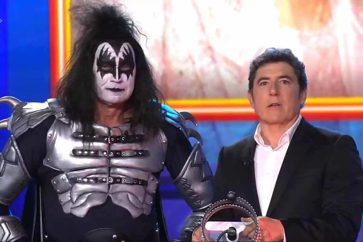 Bertín Osborne y Manel Fuentes en un escenario, una vestida con un traje metálico y maquillaje llamativo, y la otra con traje formal en Tu Cara Me Suena. Bertín Osborne y Manel Fuentes en un escenario, una vestida con un traje metálico y maquillaje llamativo, y la otra con traje formal en Tu Cara Me Suena.