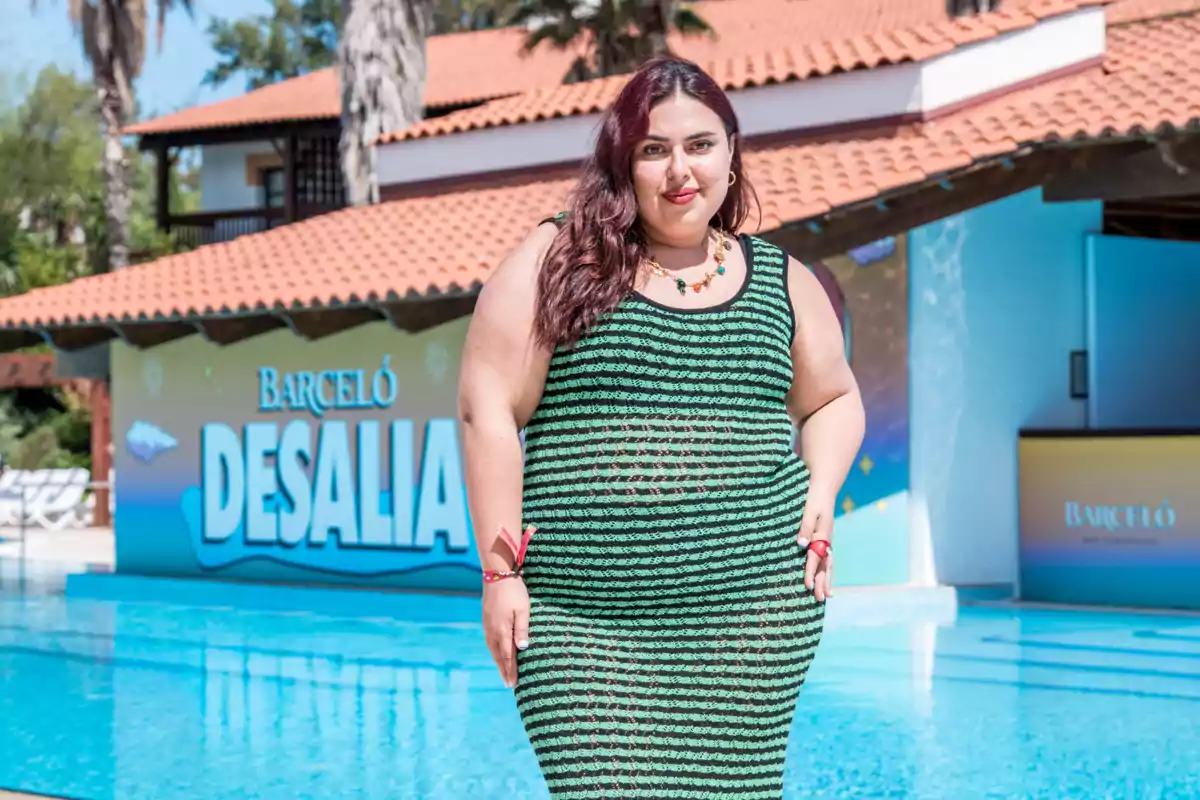 Blanca Martínez amb vestit de ratlles verdes i negres posant al costat d’una piscina amb un cartell de Barceló Desalia al fons