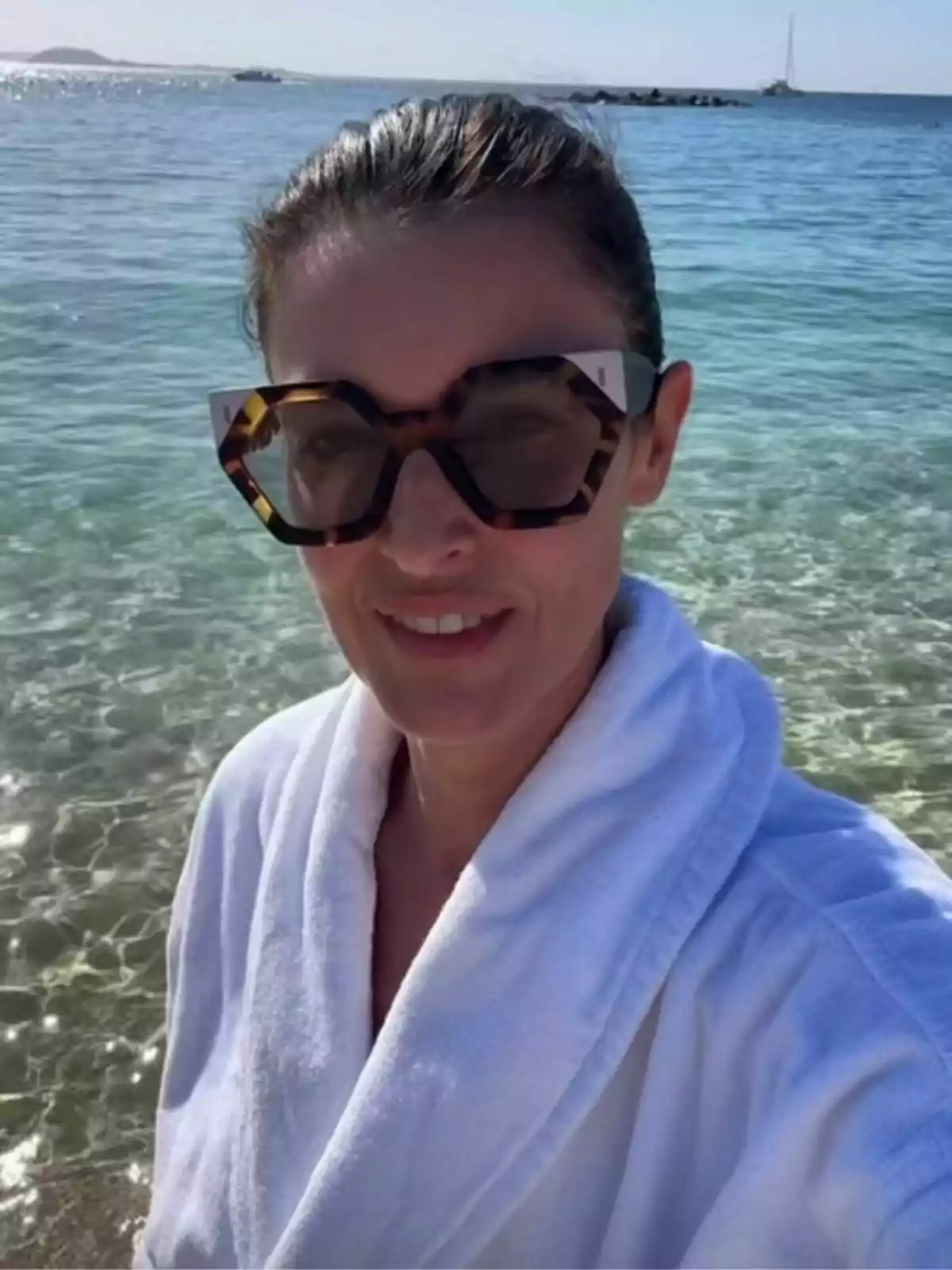 Blanca Romero amb ulleres de sol i bata blanca a la platja amb el mar de fons. Blanca Romero amb ulleres de sol i bata blanca a la platja amb el mar de fons.