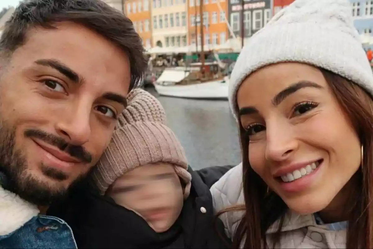 Borja González y Ana López sonriente con un niño pequeño en un lugar pintoresco con edificios coloridos y un barco al fondo. Borja González y Ana López sonriente con un niño pequeño en un lugar pintoresco con edificios coloridos y un barco al fondo.