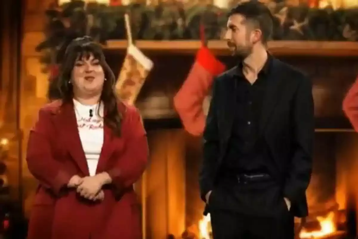 David Broncano y Lalachus están de pie frente a una chimenea decorada con medias navideñas y guirnaldas. David Broncano y Lalachus están de pie frente a una chimenea decorada con medias navideñas y guirnaldas.