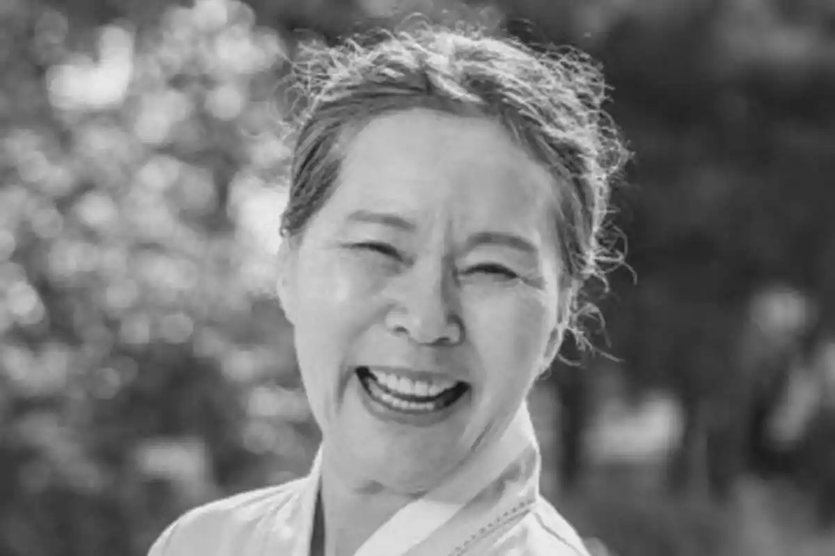 Lee Joo-Sil somrient en blanc i negre amb un fons desenfocat.