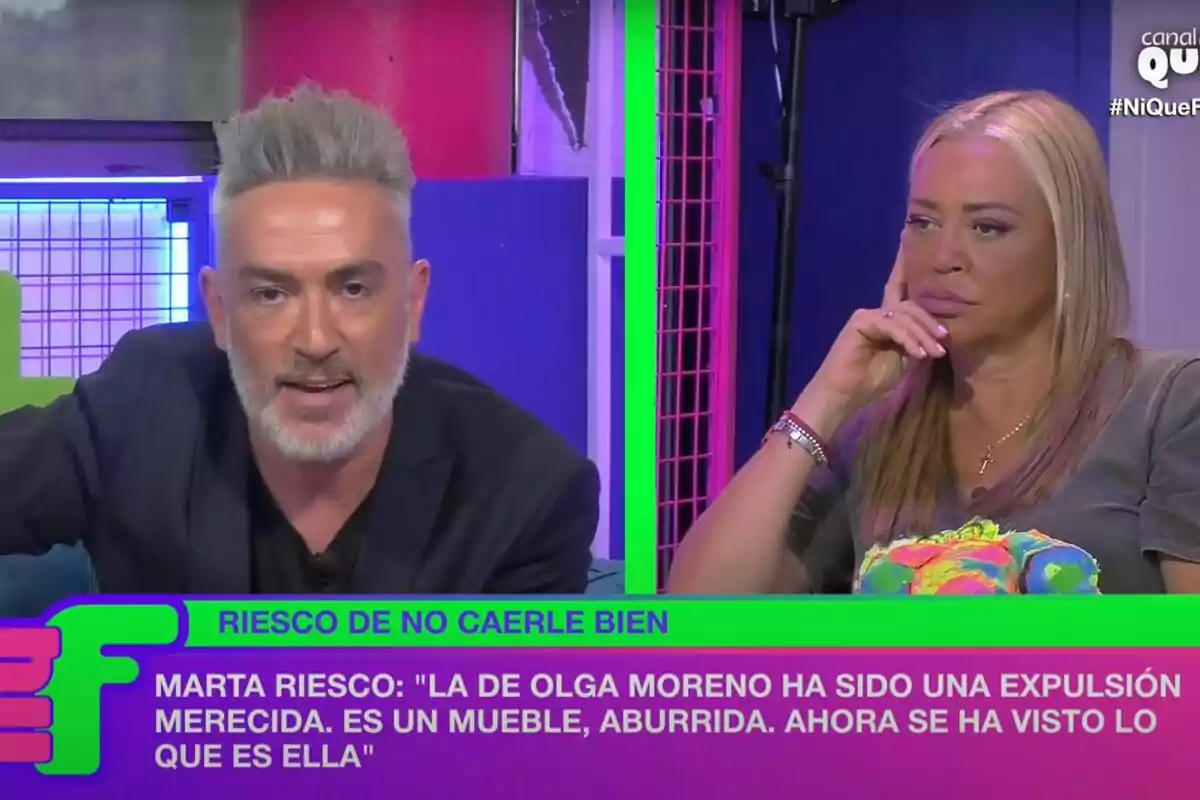 Dos personas en un programa de televisión, una de ellas hablando y la otra escuchando con expresión seria, con un texto en la parte inferior que dice: Dos personas en un programa de televisión, una de ellas hablando y la otra escuchando con expresión seria, con un texto en la parte inferior que dice:
