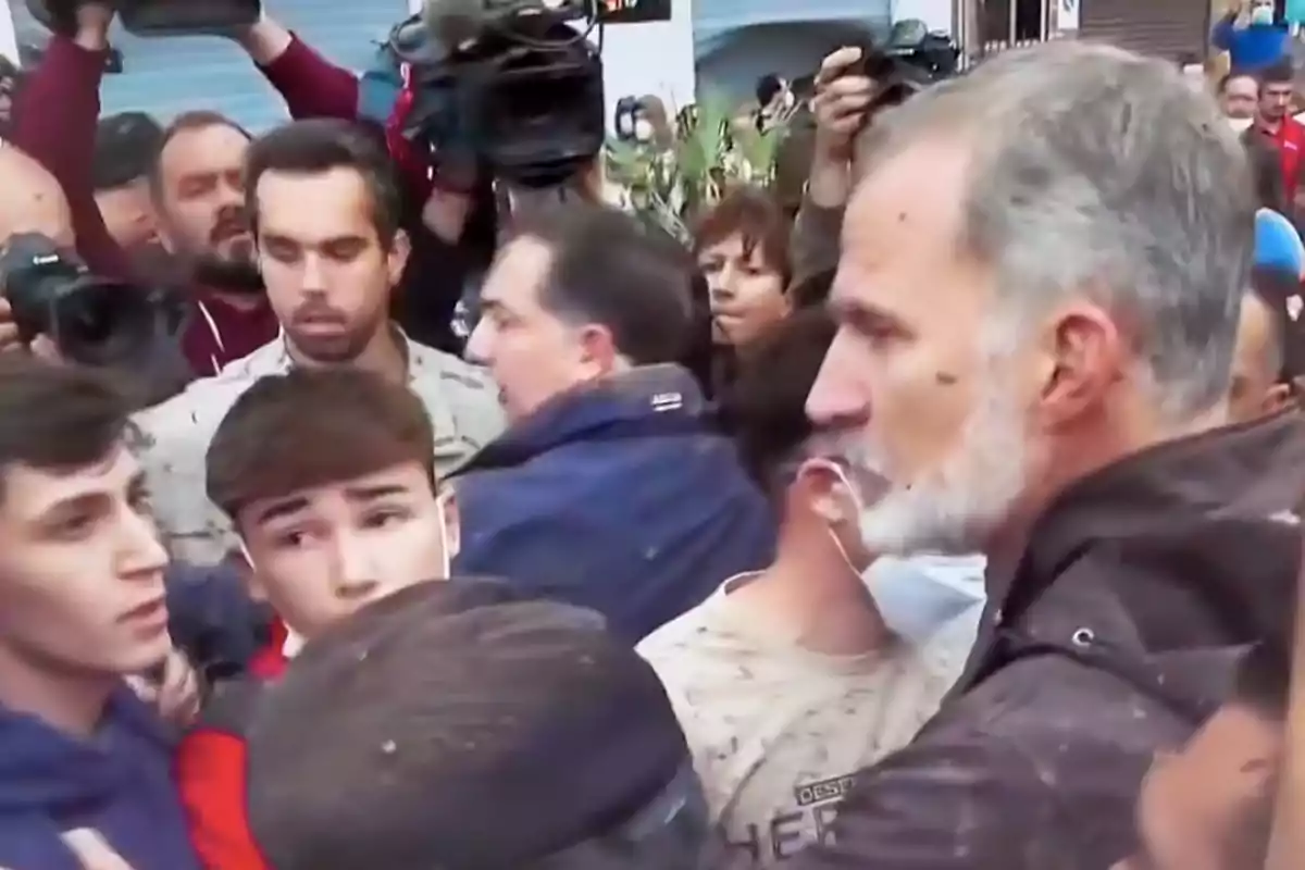 Un grupo de personas rodeadas de cámaras y periodistas en un evento público. Un grupo de personas rodeadas de cámaras y periodistas en un evento público.