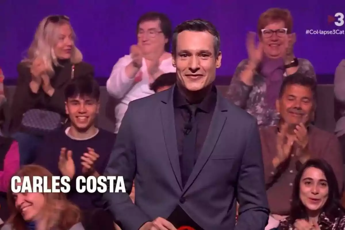 Carles Costa en Col·lapse sonríe mientras el público aplaude en un programa.