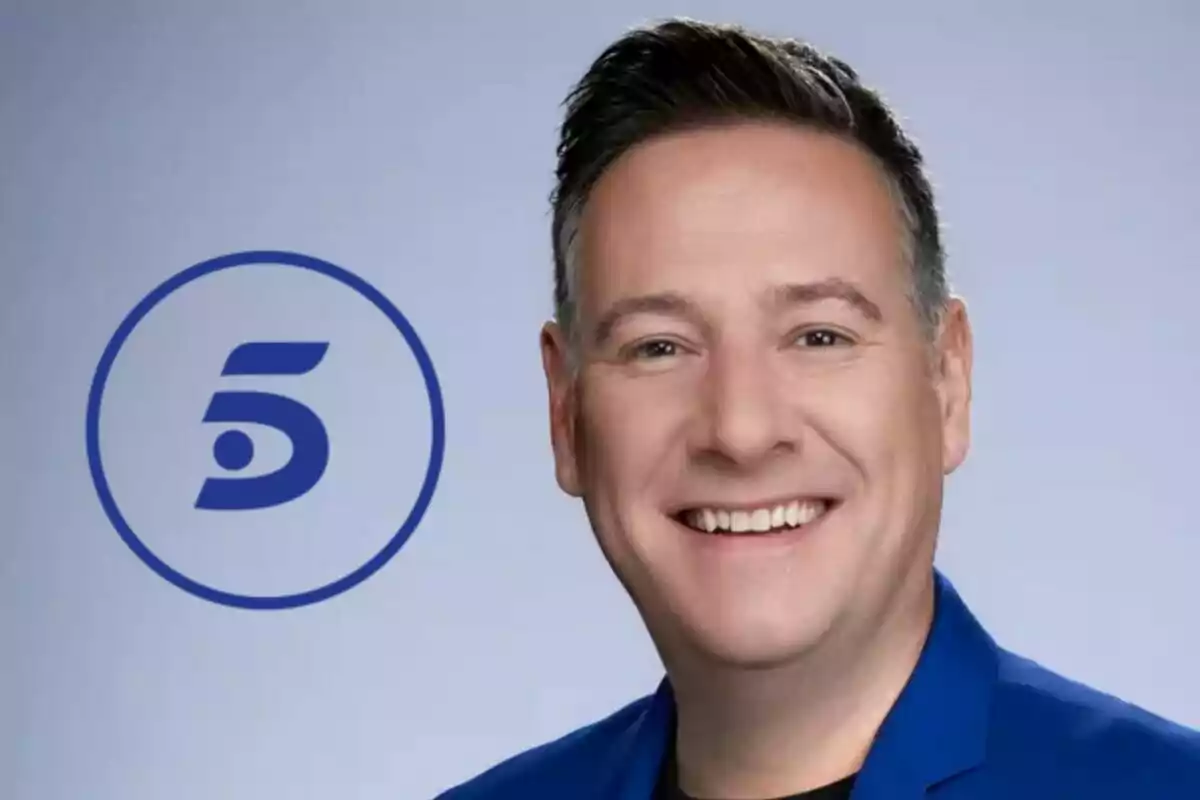 Carlos Latre somrient amb jaqueta blava al costat del logotip d'un canal de televisió (Telecinco).