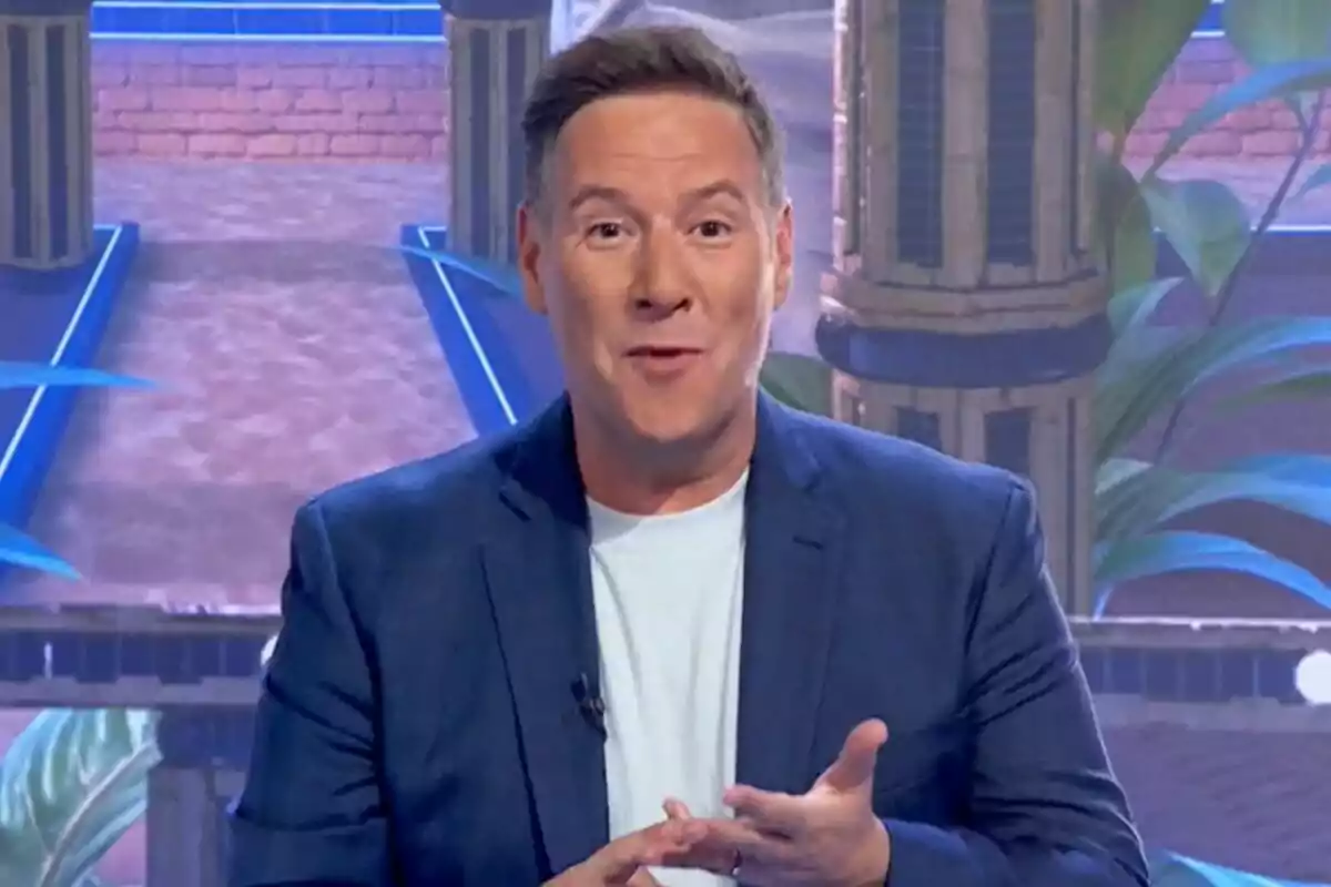 Captura de Carlos Latre amb americana blava i samarreta blanca parlant davant d'un fons colorit amb columnes i plantes al plató de Babylon Show Captura de Carlos Latre amb americana blava i samarreta blanca parlant davant d'un fons colorit amb columnes i plantes al plató de Babylon Show