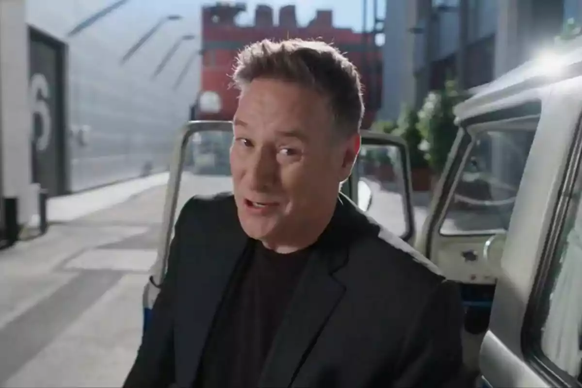 Captura de Carlos Latre amb una jaqueta negra està dreta al costat d'una camioneta amb la porta oberta a les instal·lacions de Mediaset en una promo de Babylon Show Captura de Carlos Latre amb una jaqueta negra està dreta al costat d'una camioneta amb la porta oberta a les instal·lacions de Mediaset en una promo de Babylon Show
