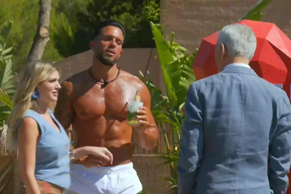Carlos Sobera, Arianna Aragón y un soltero de First Dates Hotel conversan al aire libre, una mujer y un hombre sin camisa con un cóctel en la mano, y un hombre mayor de espaldas con traje. Carlos Sobera, Arianna Aragón y un soltero de First Dates Hotel conversan al aire libre, una mujer y un hombre sin camisa con un cóctel en la mano, y un hombre mayor de espaldas con traje.