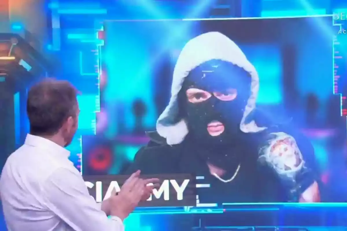Pablo Motos de espaldas observa una pantalla que muestra a Ceciarmy con pasamontañas y capucha en la pantalla de El Hormiguero. Pablo Motos de espaldas observa una pantalla que muestra a Ceciarmy con pasamontañas y capucha en la pantalla de El Hormiguero.