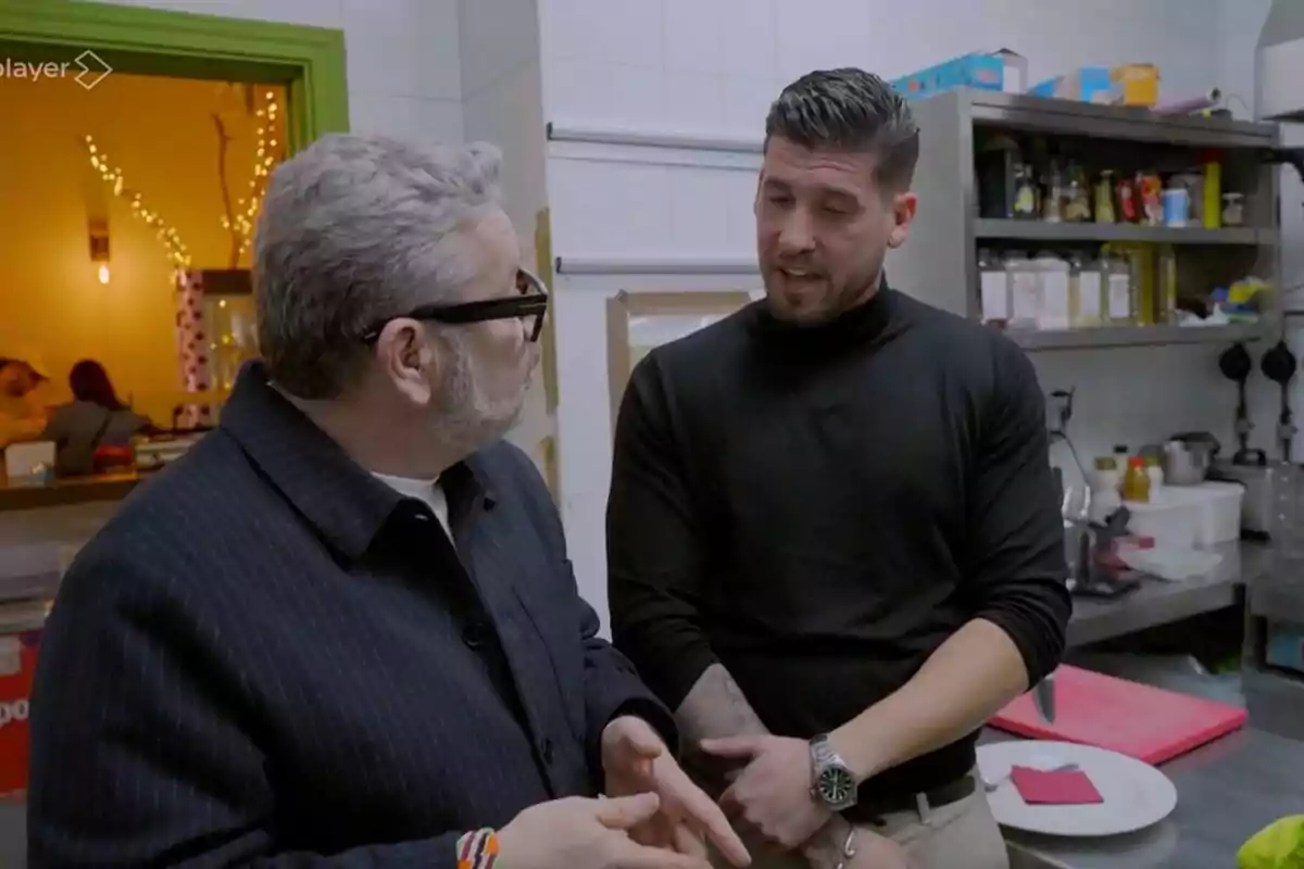 Dues persones conversant en una cuina, Alberto Chicote porta ulleres i l'altra porta un jersei negre a 'Batalla de Restaurants'.