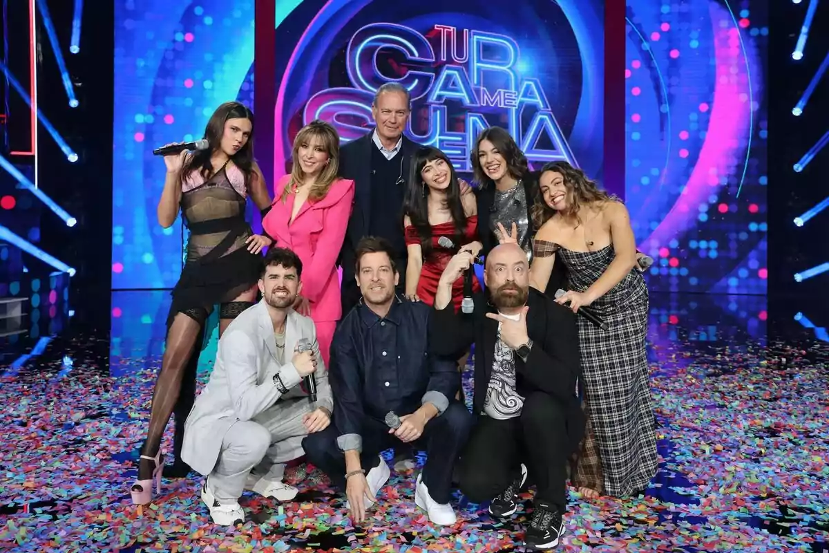 Un grupo de personas formado por Bertín Osborne, Ana Guerra, Manu Baqueiro, Gisela, Goyo Jiménez, Yenesi, Esperansa Grasia, Melani García y Mikel Herzog Jr. posando juntas en el plató de Tu Cara Me Suena lleno de confeti, algunas sosteniendo micrófonos y sonriendo a la cámara, con un fondo colorido y un letrero que parece ser parte del programa. Un grupo de personas formado por Bertín Osborne, Ana Guerra, Manu Baqueiro, Gisela, Goyo Jiménez, Yenesi, Esperansa Grasia, Melani García y Mikel Herzog Jr. posando juntas en el plató de Tu Cara Me Suena lleno de confeti, algunas sosteniendo micrófonos y sonriendo a la cámara, con un fondo colorido y un letrero que parece ser parte del programa.