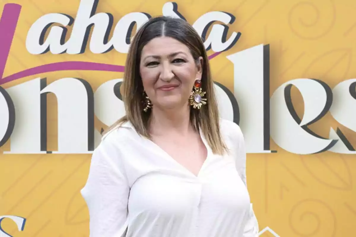 Fotografía de Cruz Morcillo vestida con una blusa blanca y usando aretes grandes, está de pie frente a un fondo amarillo durante la presentación de Y ahora Sonsoles Fotografía de Cruz Morcillo vestida con una blusa blanca y usando aretes grandes, está de pie frente a un fondo amarillo durante la presentación de Y ahora Sonsoles