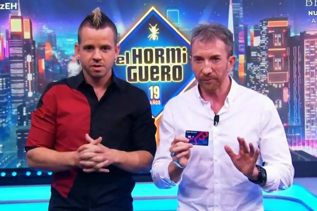 Dabiz Muñoz y Pablo Motos en un set de televisión con un fondo colorido y un cartel que dice Dabiz Muñoz y Pablo Motos en un set de televisión con un fondo colorido y un cartel que dice