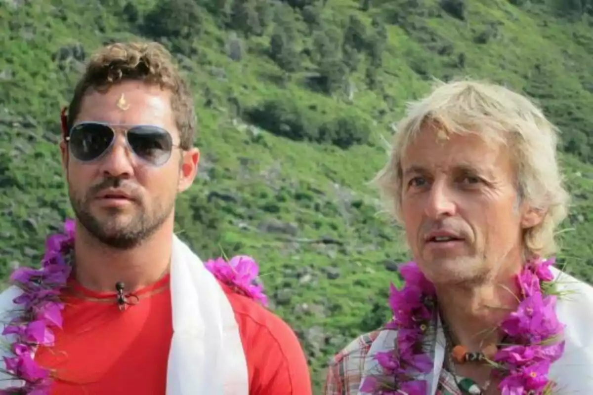 David Bisbal y Jesús Calleja con collares de flores y ropa casual posan al aire libre con un fondo de vegetación en Universo Calleja.