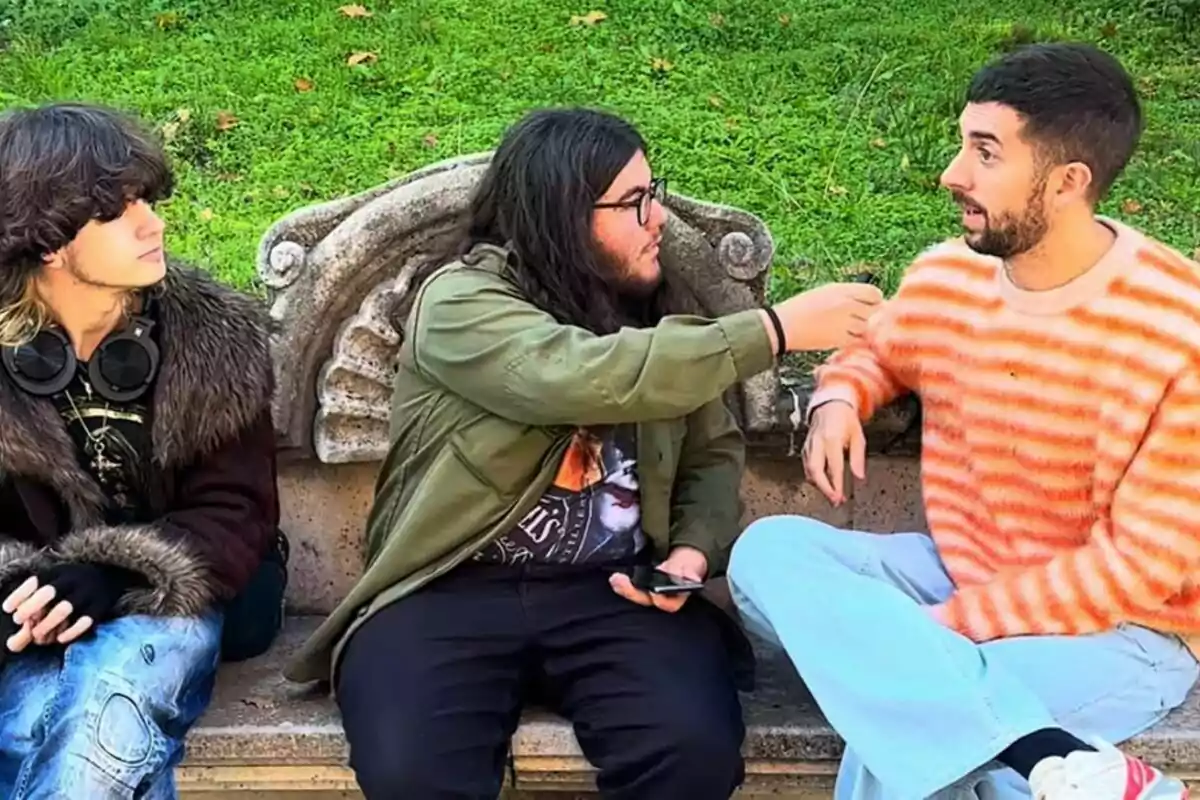 David Broncano siendo entrevistado por Detective Murciano y Zorrorífico sentados en un banco de piedra en un parque. David Broncano siendo entrevistado por Detective Murciano y Zorrorífico sentados en un banco de piedra en un parque.